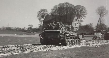 Men of the Herefordshire Regiment approach the Petershagen bridge on the back of Fife and Forfar Yeomanry tanks.