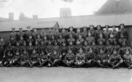 A squad of soldiers - probably recruits to the Herefordshire Regiment -  in Friars St Barracks - taken during The First World War. St Nicholas Church Tower in the background.
