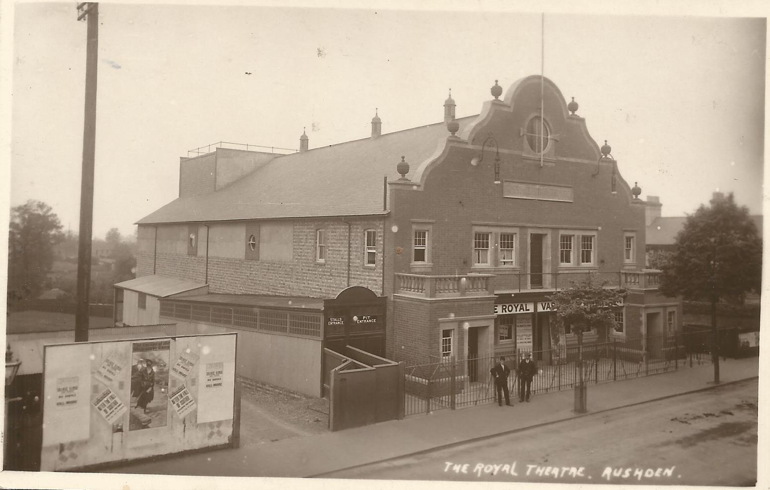 The Royal Variety Theatre was built on a site in High Street North known as Marriott’s Ground. It opened on Saturday 23rd September 1911 with films and variety (although, despite the name, it always favoured films) – no doubt many soldiers from the Battalion visited ‘The Royal’. There was seating for approximately 900, in stalls and balcony. Shows were twice nightly, at 7pm and 9pm, and an orchestra, under the direction of Henry J. Baker, accompanied the films and variety turns. The Royal Theatre closed on Saturday 13th May 1961. The building was converted into a car sales showroom. It was demolished in 2005; an ASDA store has been built over the site. The original photograph is taken from an elevated position, and on ‘walking the ground’ it appears that it was taken from the end of Rushden Railway Station. The rail lines ran over a bridge where the photographer probably stood. The station and line are now closed, but the station retained as a historic site, the road bridge has been demolished but the supports to each side of the road are visible in the modern picture. Also enclosed is a photo of the end of the station platform which would have overlooked The Royal.